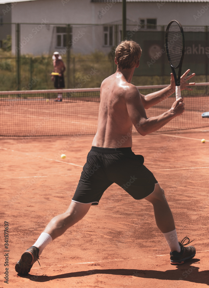 A man plays tennis on the court in the park.