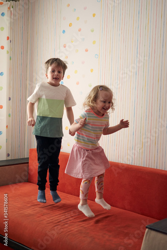 Two happy children boy and girl have a pillow fight at home. Family fun. Quarantine covid-19 and closed school during coronavirus outbreak. photo