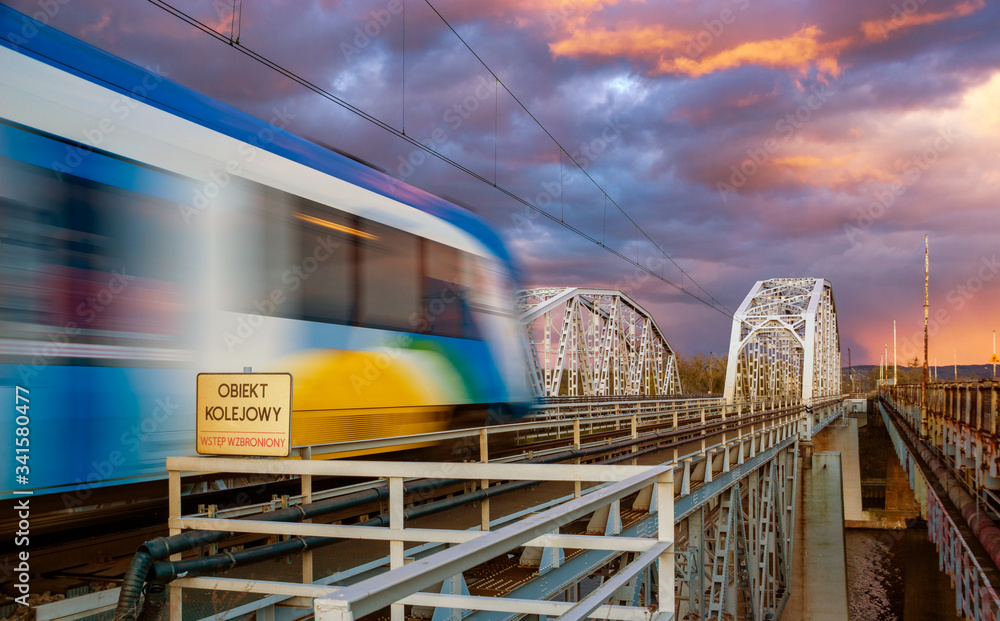 Passenger train entering the truss bridge during a dramatic evening storm Passenger train entering the truss bridge during a dramatic evening storm
