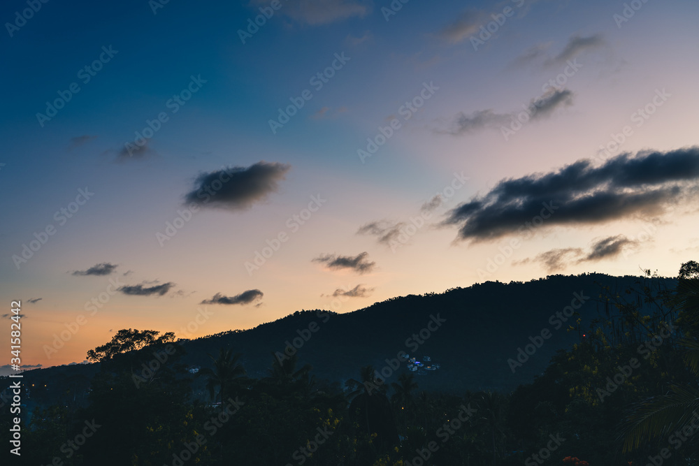 Sunset over trees, sea and mountains on a tropical island