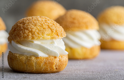 Chou pastry biscuits filled with whipped cream on grey background. Concept: bakery, french dessert. Selective focus. photo