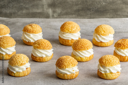 Chou pastry biscuits filled with whipped cream on grey background. Concept: bakery, french dessert.  photo