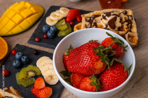 Tasty breakfast - close-up of strawberries with homemade waffles with fresh orange juice  fruit  milk and yogurt