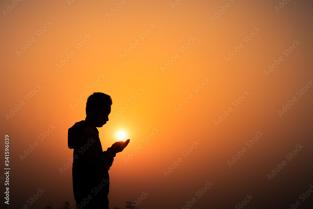 Boy praying to God on the mountain with light sunset background, Christians should worship and thank God, Christian silhouette concept.
