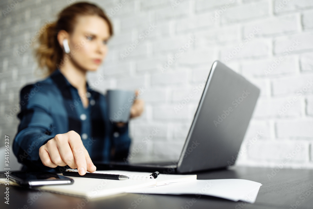 Girl freelancer sitting at table with laptop, focus on hand Girl freelancer sitting at table with laptop, focus on hand