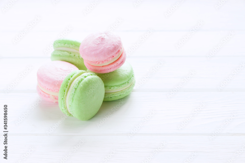 Sweet ?olorful pink and green macaroons. A french sweet delicacy. White wooden board, empty space Sweet ?olorful pink and green macaroons. A french sweet delicacy. White wooden board, empty space