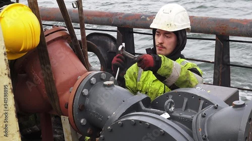 Natig Aliev tanker sailor in helmet completes fuel gauge setting with silver wrenches on way to Skagen harbour