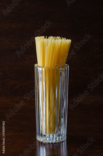 Spaghetti in a glass cup on a brown wooden table. photo