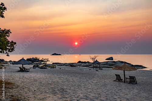 Idyllic beach with tables and sun loungers at sunrise photo