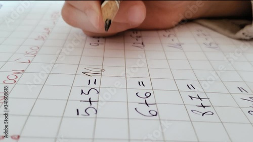 Close up of primary school kid doing math homework on excercise book,home family