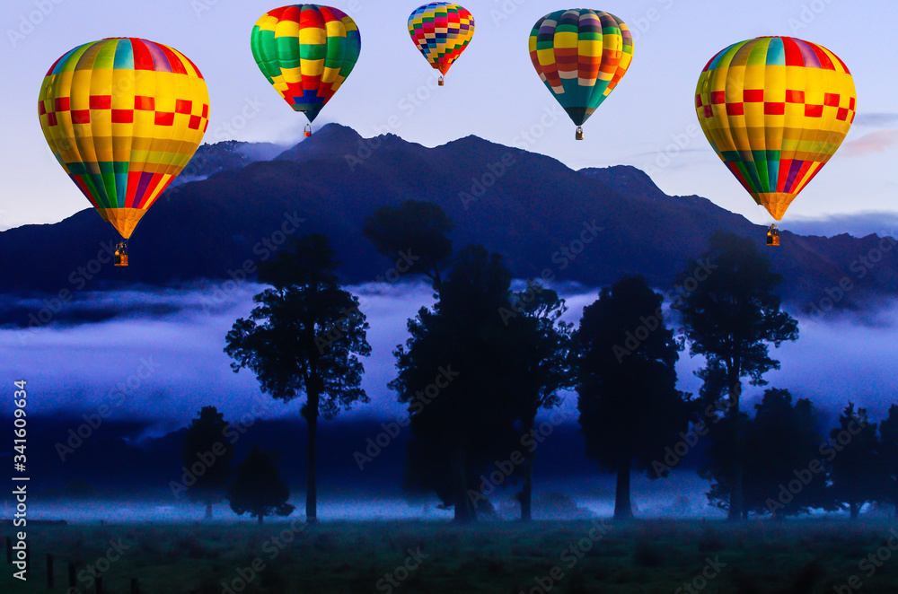Fototapeta premium Colorful Hot air balloon flying over the sky at mountains, trees and night mist