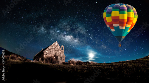 Hot air balloon flying over spectacular under the sky with and shininng star at night