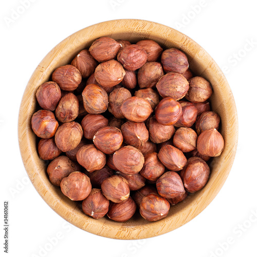 Hazelnuts in wooden bowl isolated on white. Top view.