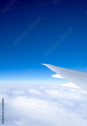 Wing of the plane on blue sky background, view from the window of an airplane.