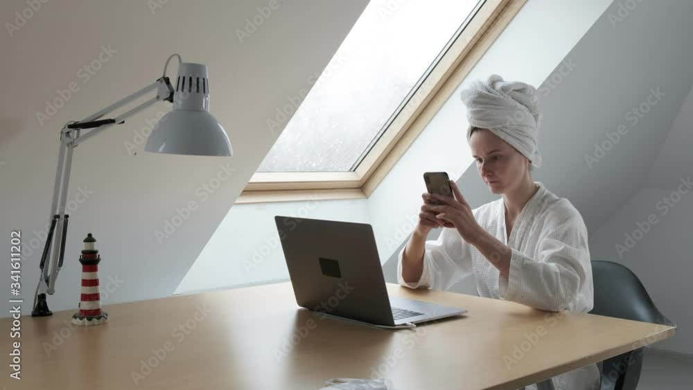 young woman at desk with computer, stares at smartphone, types. quarantine of coronavirus pandemic COVID-19. Remote work, telework at home on laptop. Online conference, distant working, homeoffice young woman at desk with computer, stares at smartphone, types. quarantine of coronavirus pandemic COVID-19. Remote work, telework at home on laptop. Online conference, distant working, homeoffice
