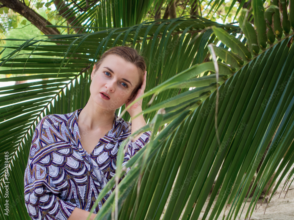 Beautiful young woman standing near palm leaves at sea. Beautiful young woman standing near palm leaves at sea.