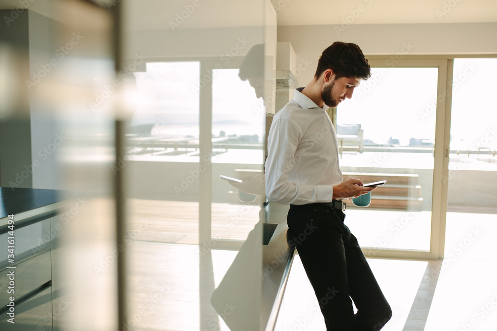 Businessman checking phone while having breakfast at home Businessman checking phone while having breakfast at home