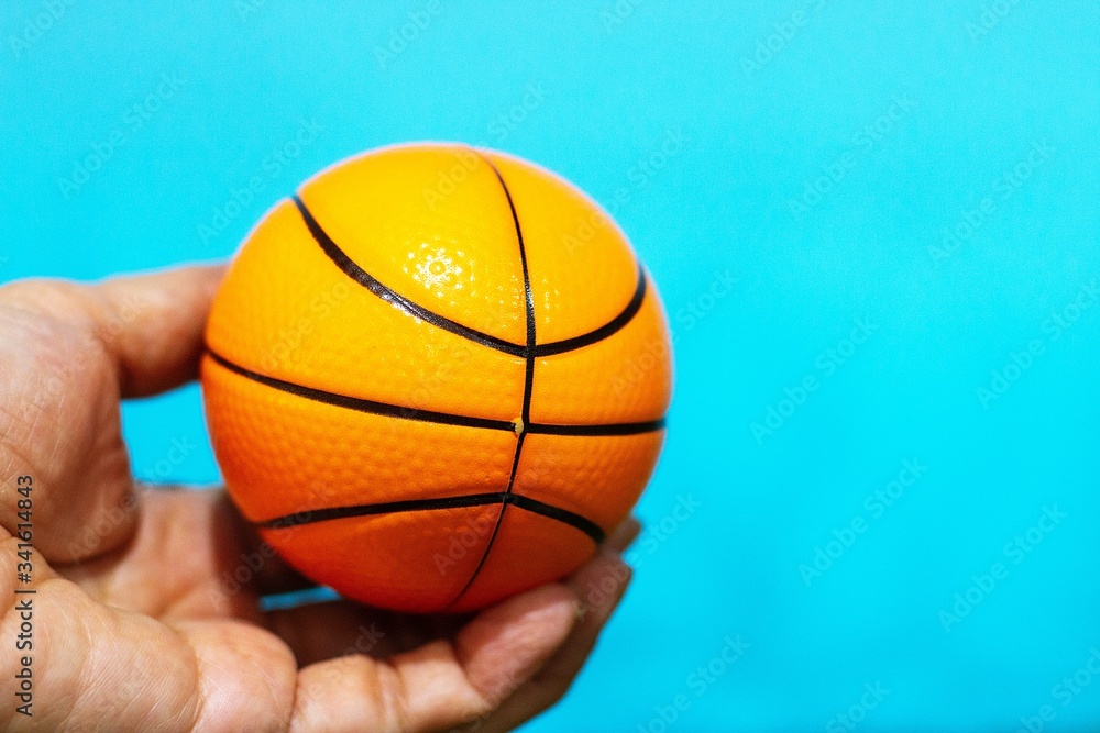 Hand is holding basketball on blue background