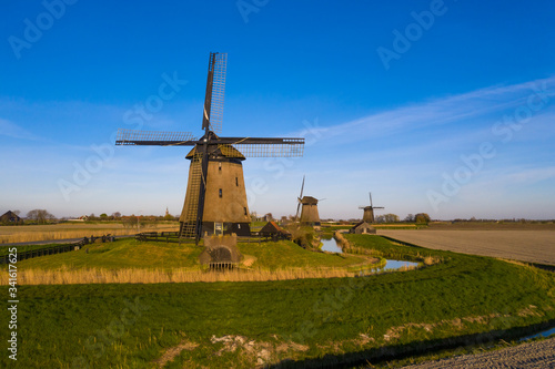 Aerial view on three dutch windmills bathing in sunlight with a blue sky 