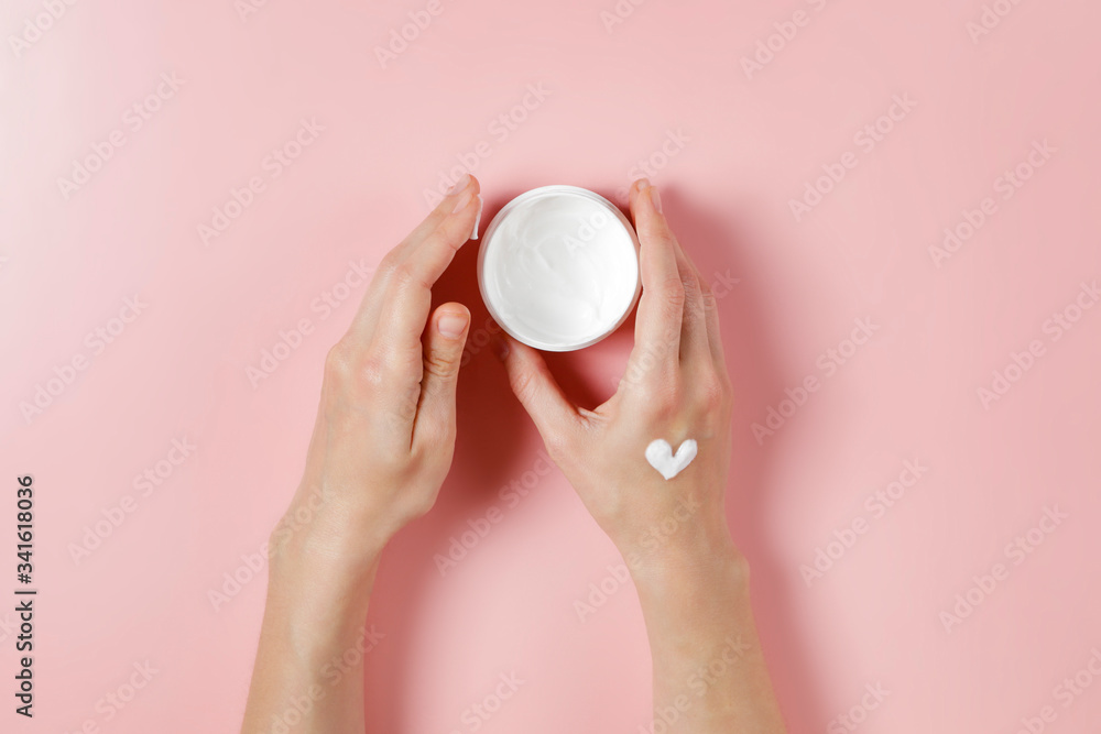 Revitalizing hand cream for healing and recovery after excessive use of soap and disinfectants. Young woman applying moisturizing lotion. Copy space, close up, pink background, flat lay, top view. Revitalizing hand cream for healing and recovery after excessive use of soap and disinfectants. Young woman applying moisturizing lotion. Copy space, close up, pink background, flat lay, top view.