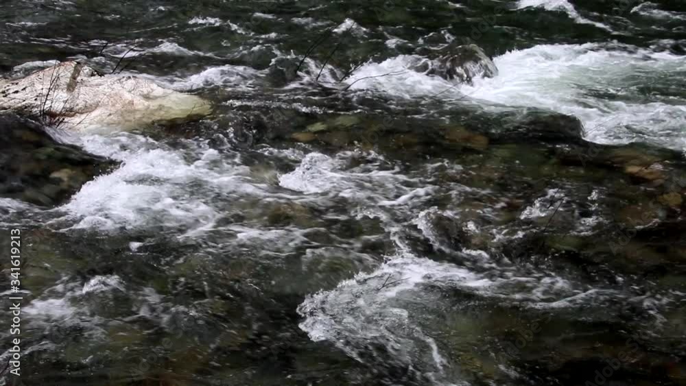 Medium high angle of a fast moving wild and scenic river with a white granite rock upper left and white water highlights cutting across the frame to front and anchoring the scene on the upper right. Medium high angle of a fast moving wild and scenic river with a white granite rock upper left and white water highlights cutting across the frame to front and anchoring the scene on the upper right.