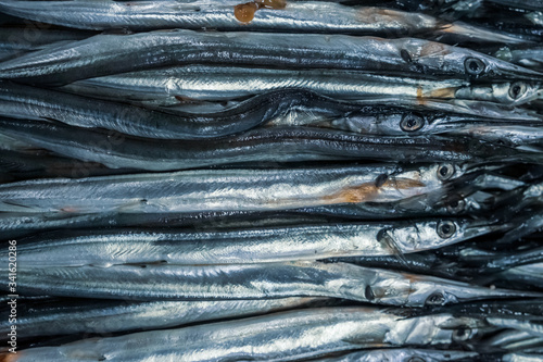 Needle fish in a box at the fishing market. Selling fresh food. Seafood, delicacy. Gourmet cuisine.