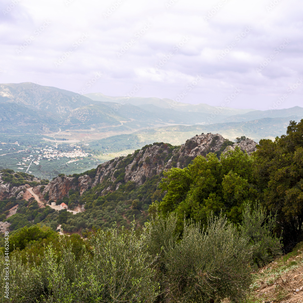 view from the mountain to a small Cretan town on a background of gray cloudy sky
