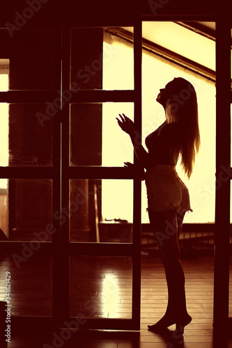sexy model in a loft home interior, back light silhouette rays of the sun evening © kichigin19