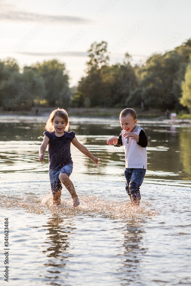 Two happy kids running through water in summer Two happy kids running through water in summer