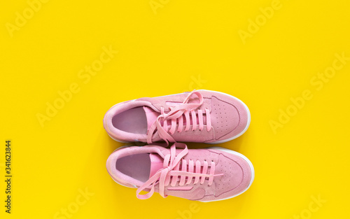 Pink nubuck sneakers isolated on a yellow background, seasonal shoes for walking and sports, top view photo