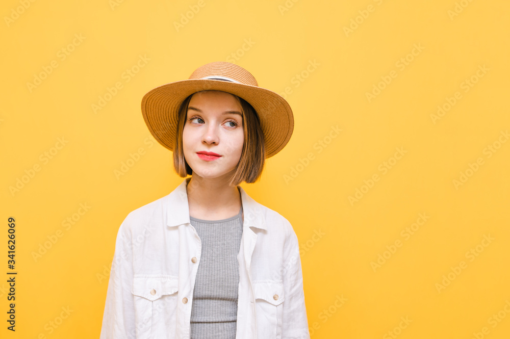 Closeup portrait of funny tourist girl in hat from hundred and white shirt on yellow background, looking away at copy space. Cute lady in summer clothes isolated on yellow background. Closeup portrait of funny tourist girl in hat from hundred and white shirt on yellow background, looking away at copy space. Cute lady in summer clothes isolated on yellow background.