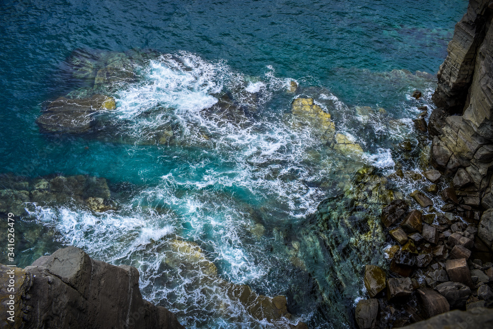 Top view of turquoise waves crashing on the rocks