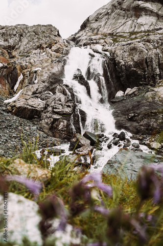 Kyrgyzstan. Mountain waterfall on grass background. Summer