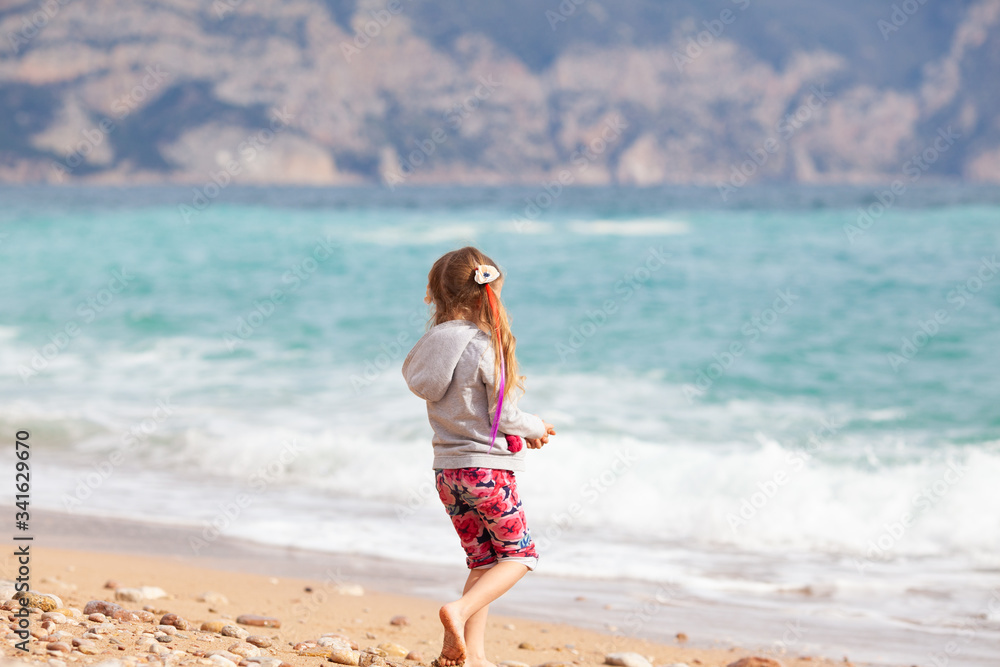 Happy pretty girl walks along the sea coast against the background of the sea, from behind a beautiful landscape Happy pretty girl walks along the sea coast against the background of the sea, from behind a beautiful landscape