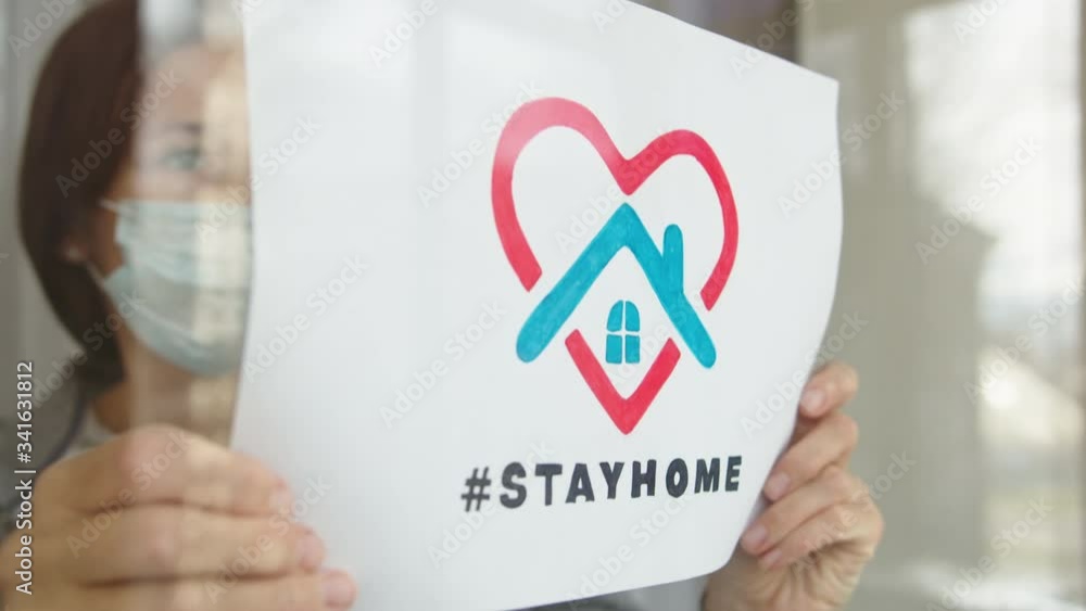 Woman showing picture with title Stay home. Woman showing picture with title Stay home.