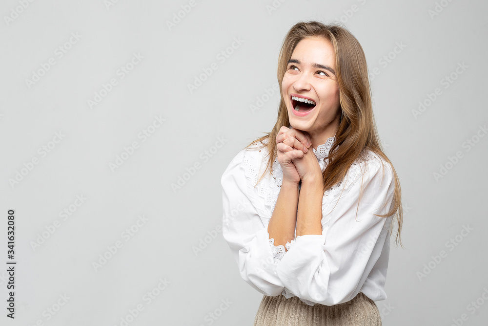 Very emotional woman laughs while tearing her stomach. Portrait of a beautiful woman on a white-gray background Very emotional woman laughs while tearing her stomach. Portrait of a beautiful woman on a white-gray background