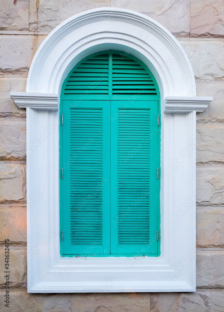 Fototapeta premium Green arched wooden window on the brick wall background.