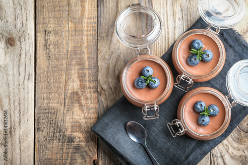 Chocolate mousse in glass jar with berries on a rustic background copy space. Homemade dessert.