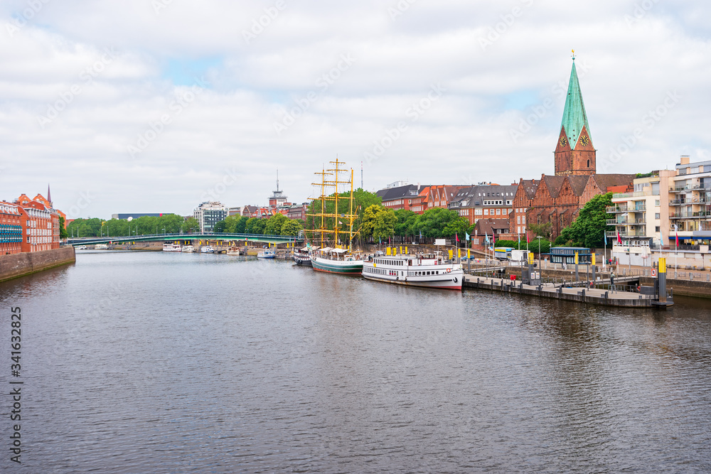 Bremen, Germany. Panoramic city view with a footbridge over the Weser River and the tower of St. Martin's Church. The boats and ships on the pier along the Promenade. Bremen, Germany. Panoramic city view with a footbridge over the Weser River and the tower of St. Martin's Church. The boats and ships on the pier along the Promenade.