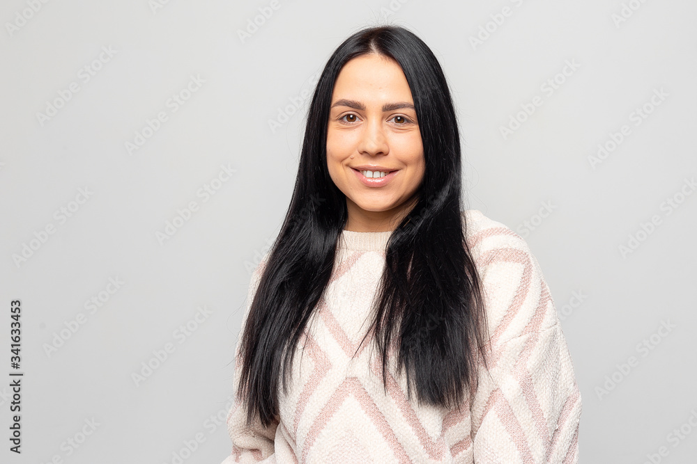Portrait of a smiling Young beautiful lovely brunette girl in a warm winter sweater on light gray background. Portrait of a smiling Young beautiful lovely brunette girl in a warm winter sweater on light gray background.