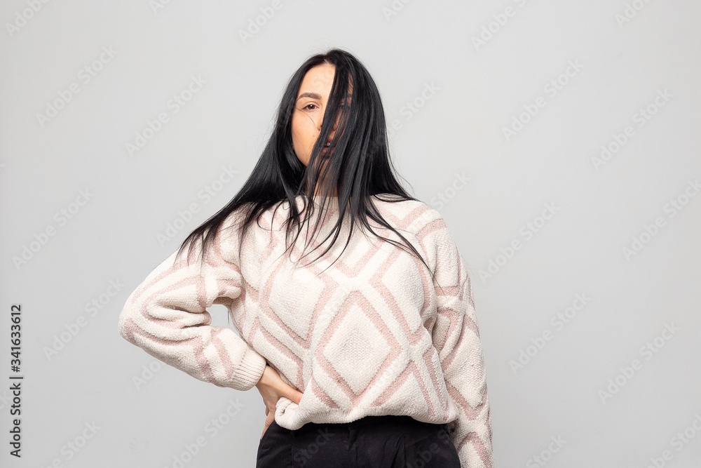 Portrait of a young beautiful cute brunette girl in a warm winter sweater on light gray background. Portrait of a young beautiful cute brunette girl in a warm winter sweater on light gray background.