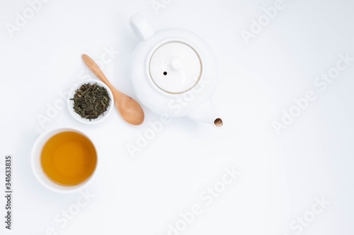 cup with tea and teapot on white background, over light 
