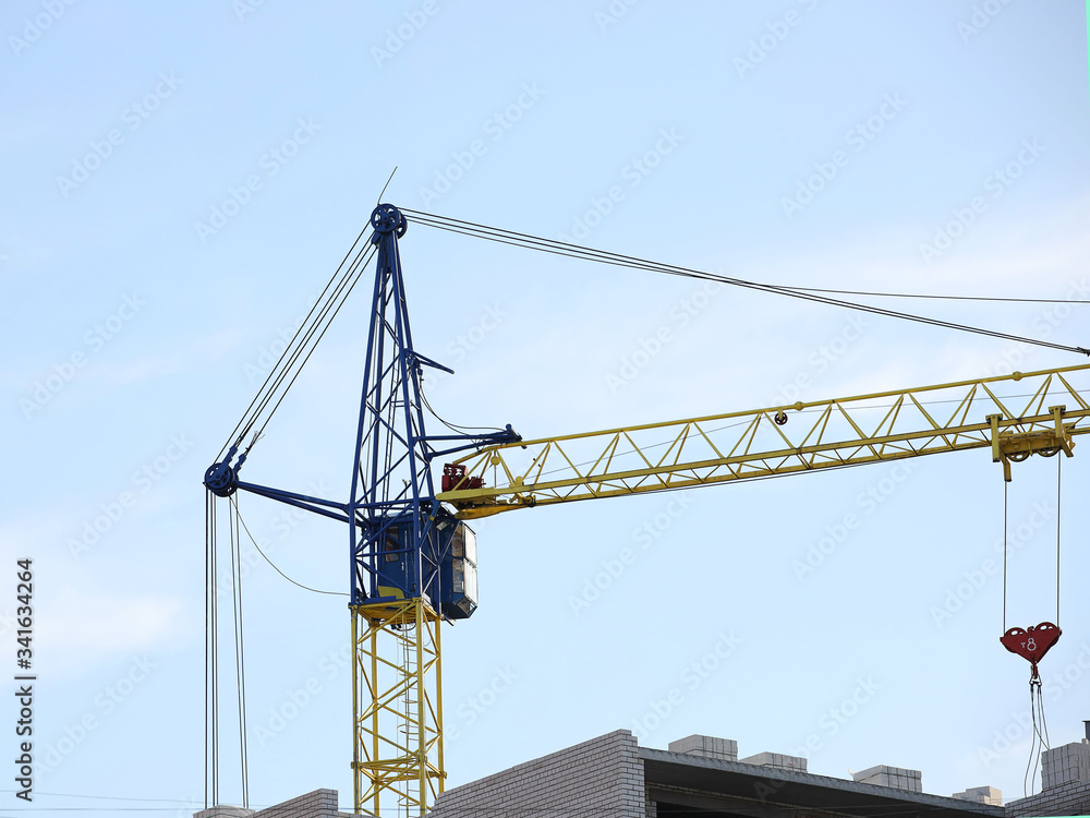 Tower cranes work during the construction of a multi-story building. New apartments for residents and premises for offices. Risky work at height. Lifting heavy building materials. City development Tower cranes work during the construction of a multi-story building. New apartments for residents and premises for offices. Risky work at height. Lifting heavy building materials. City development