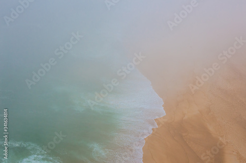 Sea and sandy beach in dense fog, autumn day photo