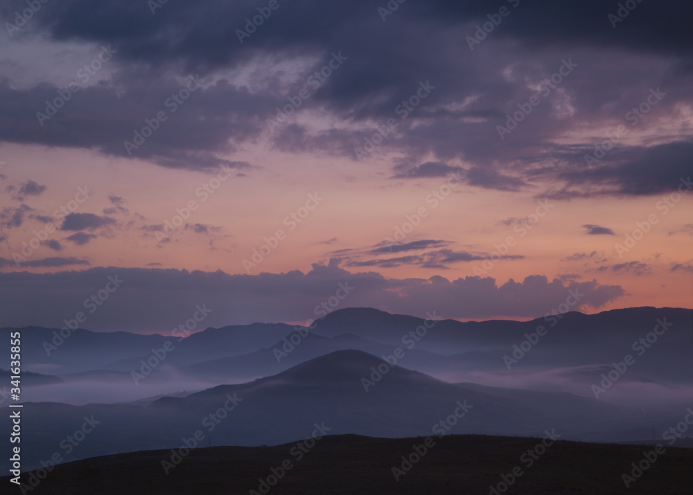 Fototapeta premium Mystical landscape with hills and fog in the evening