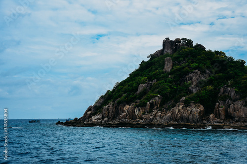 Scenic view on small island under blue sky background. Small island in a sea. 