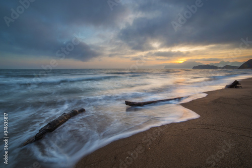 Long exposure seascape with beach and mountains at sunset