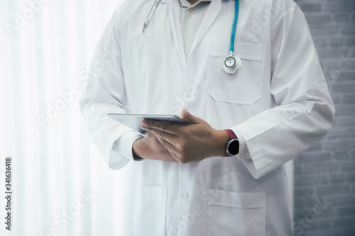 Doctor standing with stethoscope and holding tablet computer. Technology and medical concept.