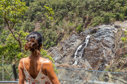 Woman looking at waterfall. Kuranda Scenic Railway Train. Tourist train journey across waterfalls  rainforest and jungles in Cairns Australia. View of beautfiul Stoney Creek Falls. Slow Motion.