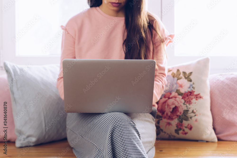 Young woman sitting on her sofa and working at her home.